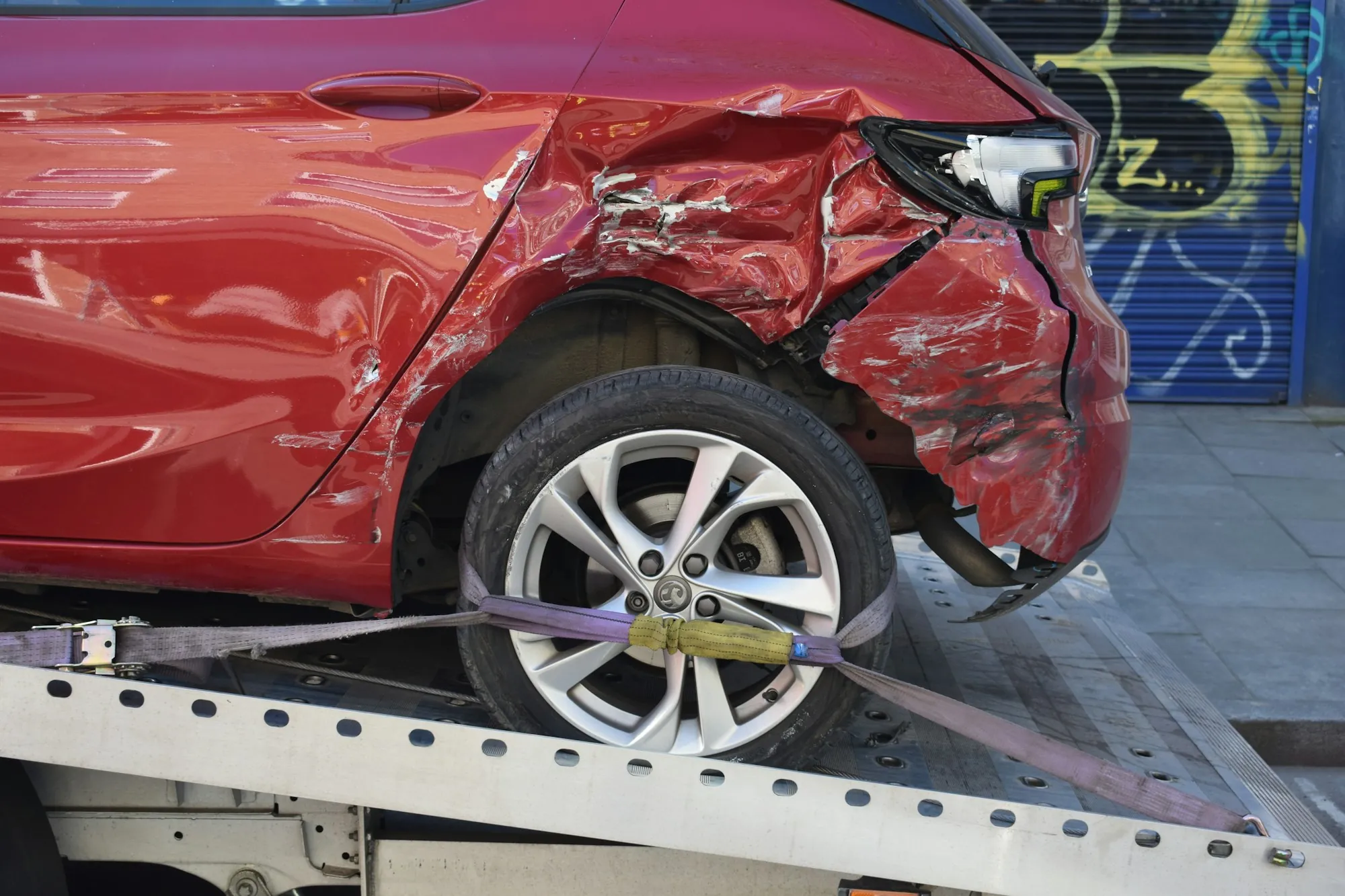 Damaged sedan secured on a flatbed tow truck on a rural roadside