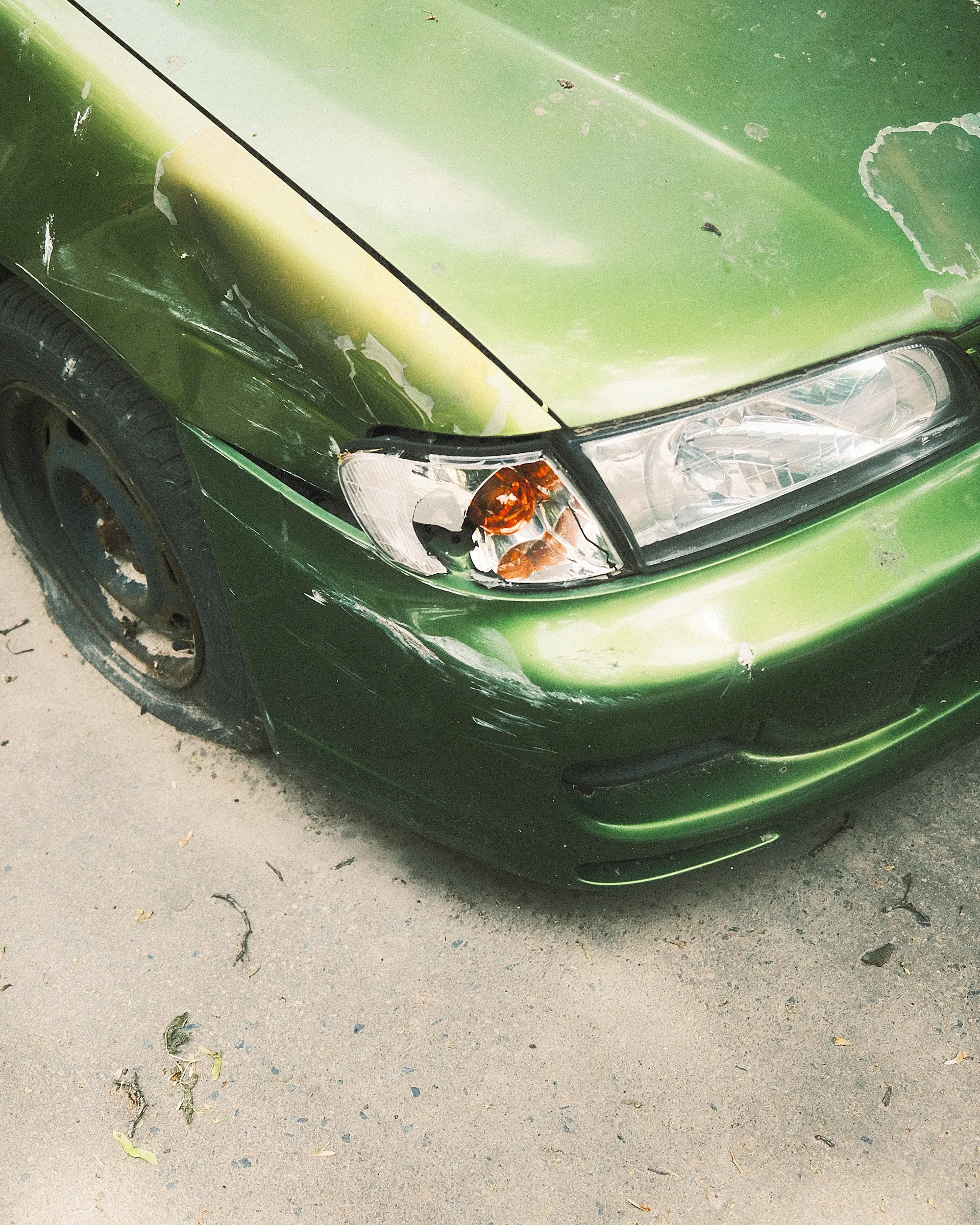 Cracked front bumper cover with a loose corner on a white SUV in a body shop