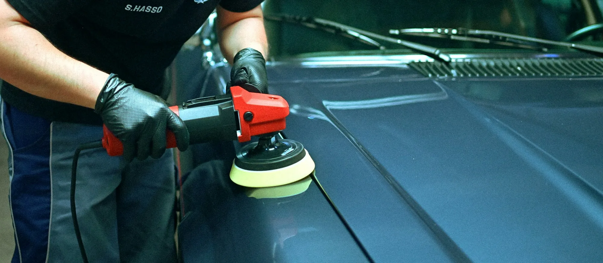 Technician buffing the paint on a dark car