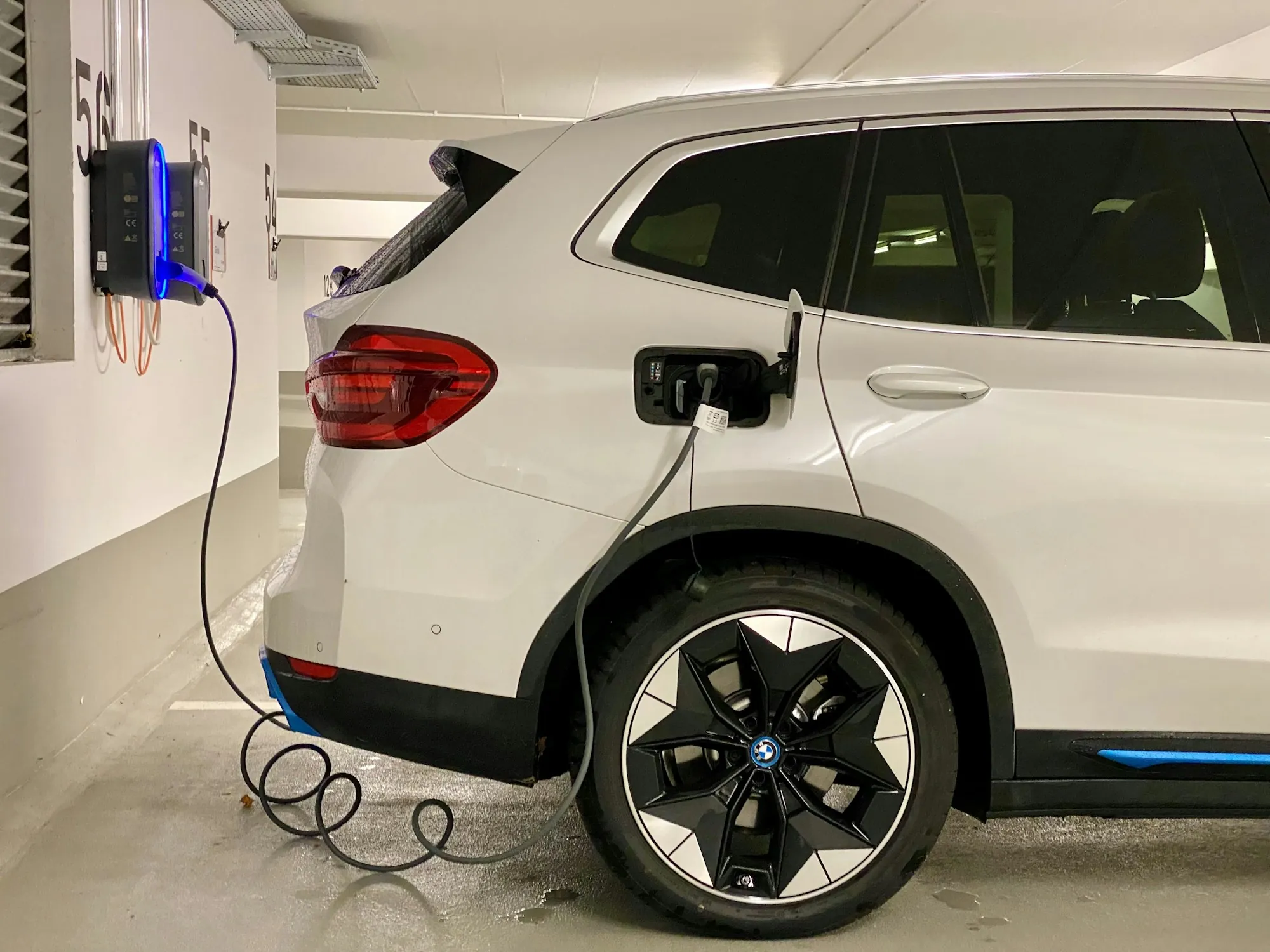 Electric car on a lift with orange high-voltage cables visible beneath the body