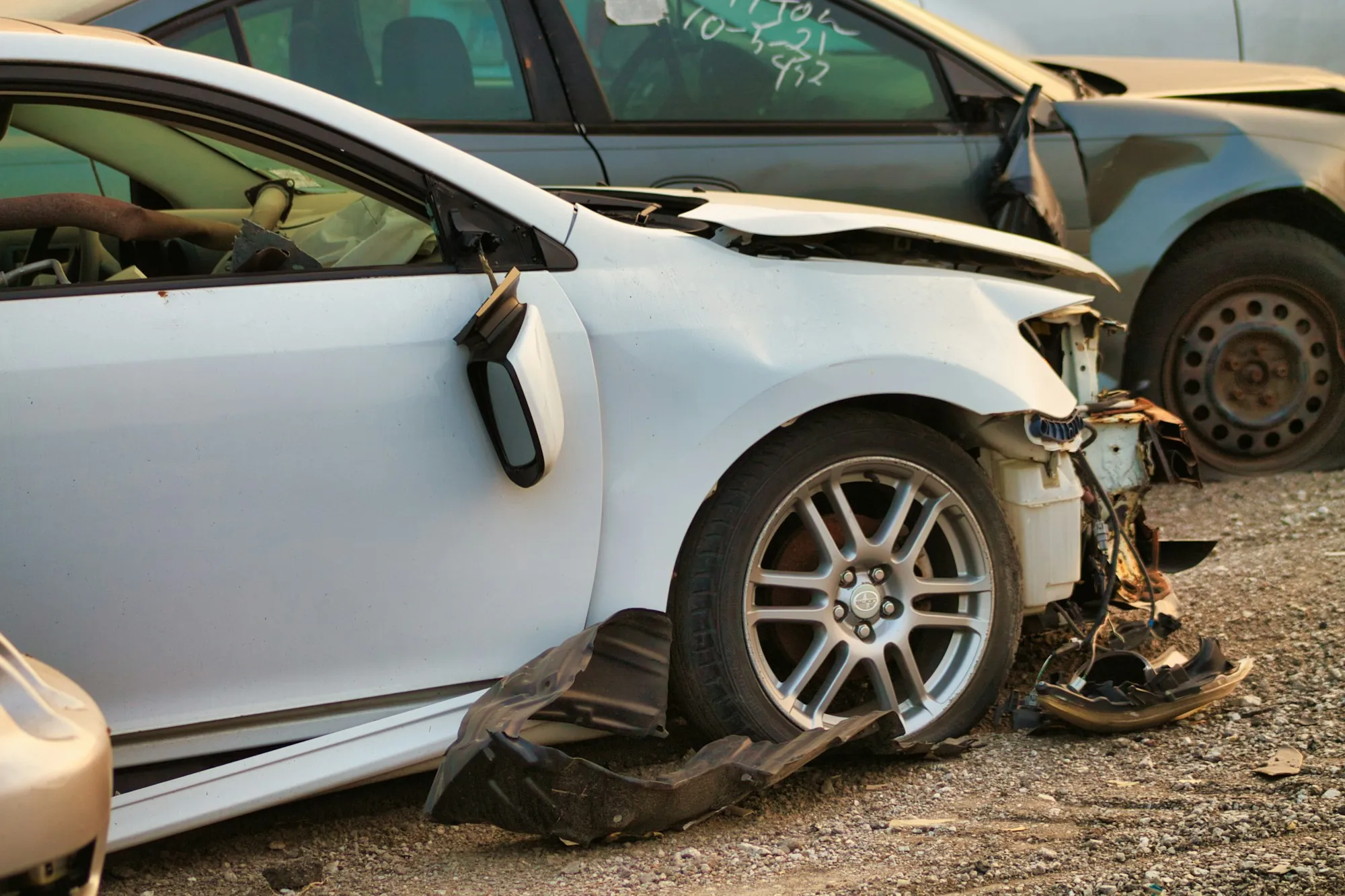 Repair estimate paperwork and damage photos spread on a counter beside a damaged car