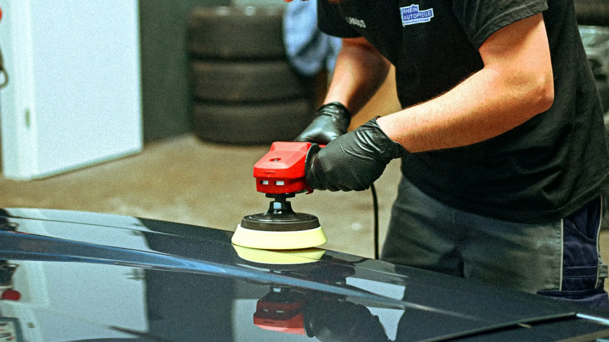 Technician using a reflection board and a long metal rod to remove a dent from a car door