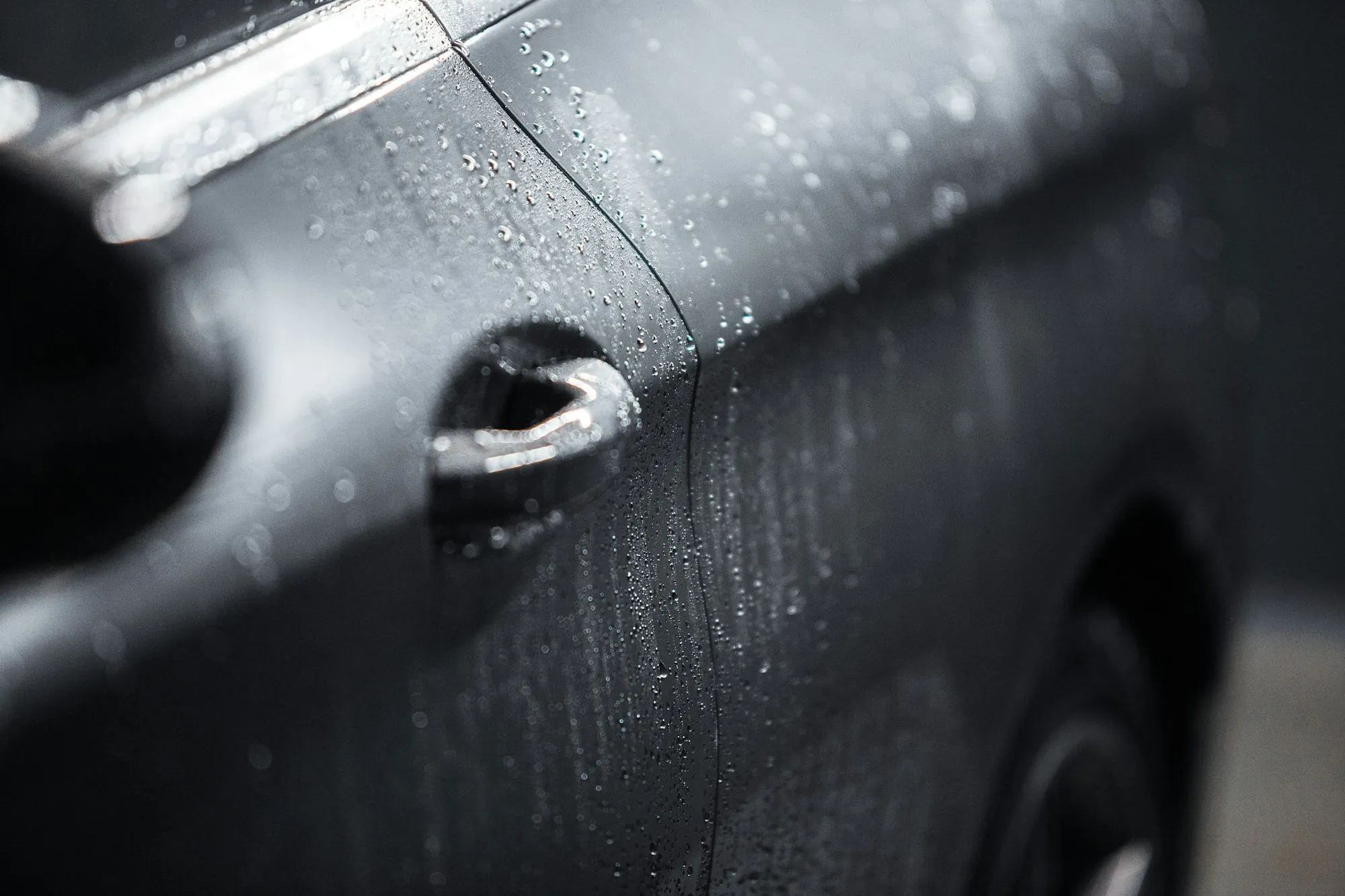Fingertip pointing to a long scratch across the rear door of a blue sedan